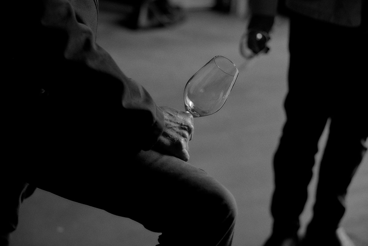 Black and white close-up of a hand holding a wine glass at Yering Station