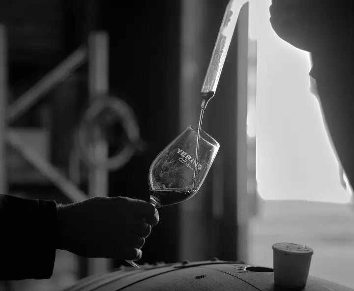 Black and white close-up of wine being poured into a Yering Station glass in the winery