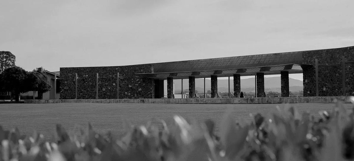 Black and white photo of a modern stone winery building with a curved roofline